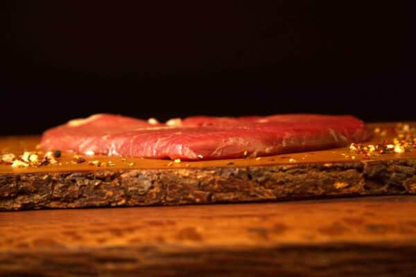 Carne natural madurada en tabla de madera con especias.