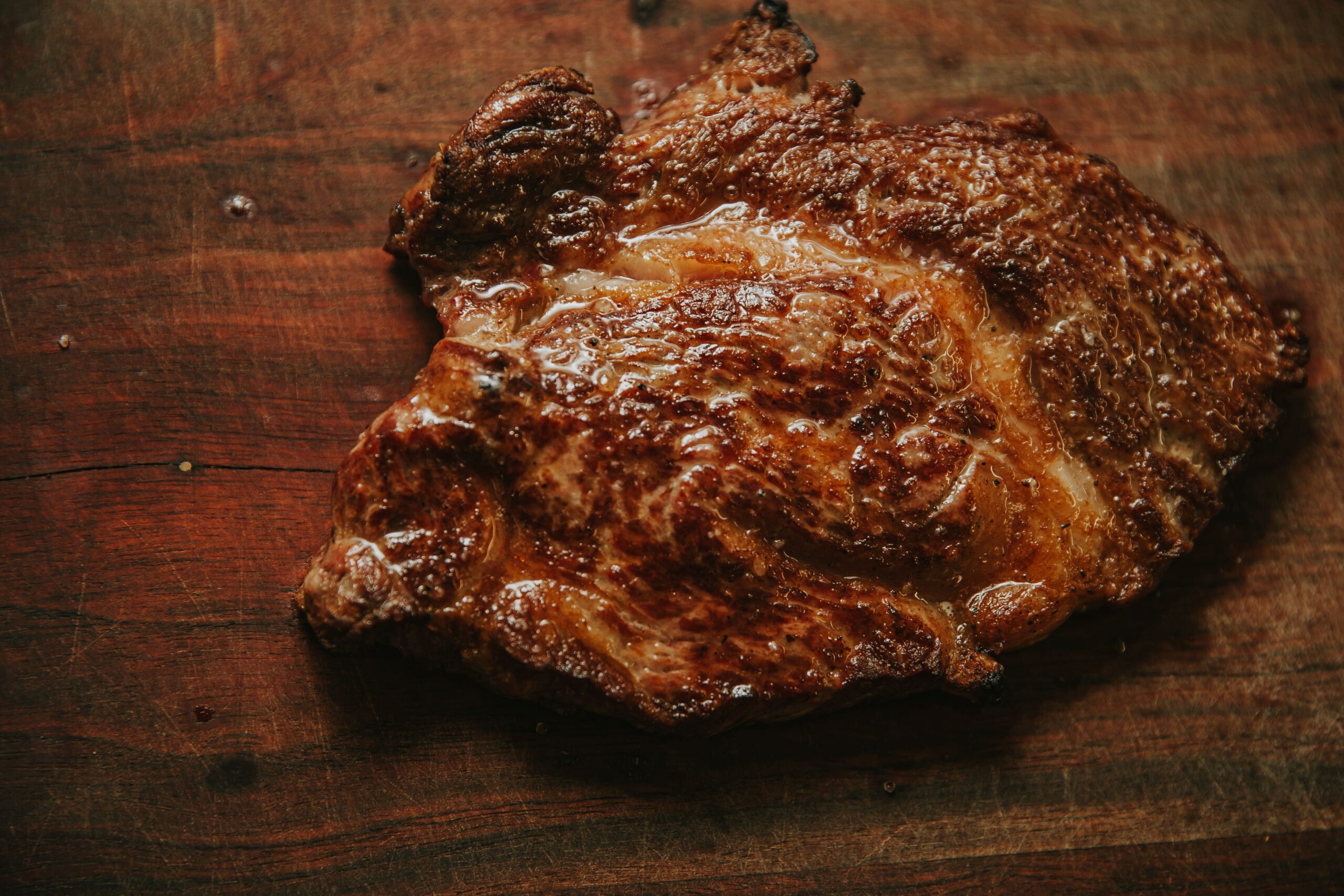 Un jugoso filete perfectamente cocido sobre un fondo rústico de madera, recién a la parrilla y suculento.